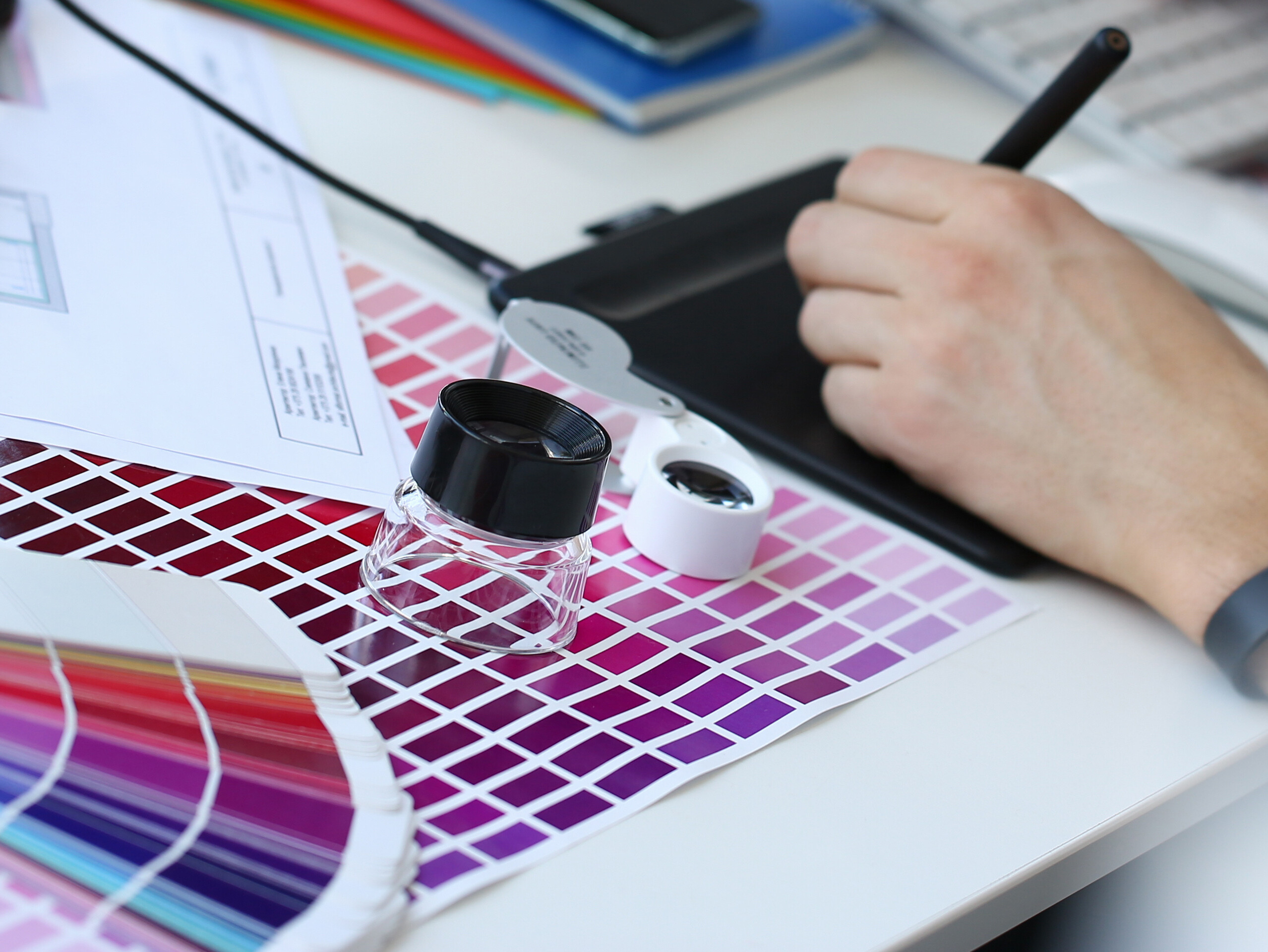 Eine Person arbeitet an einem Computer und nutzt eine Farbpalette zur kreativen Gestaltung.